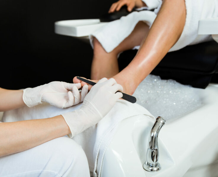 Portrait of young man doing pedicure in salon. Beauty concept.